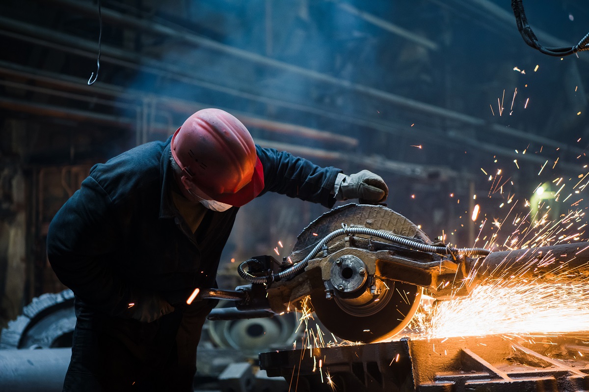 Employee grinding steel with sparks - focus on grinder. Steel factory.