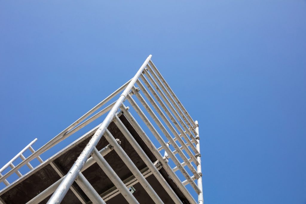 Scaffolding, metal mobile scaffold aginst blue sky background.
