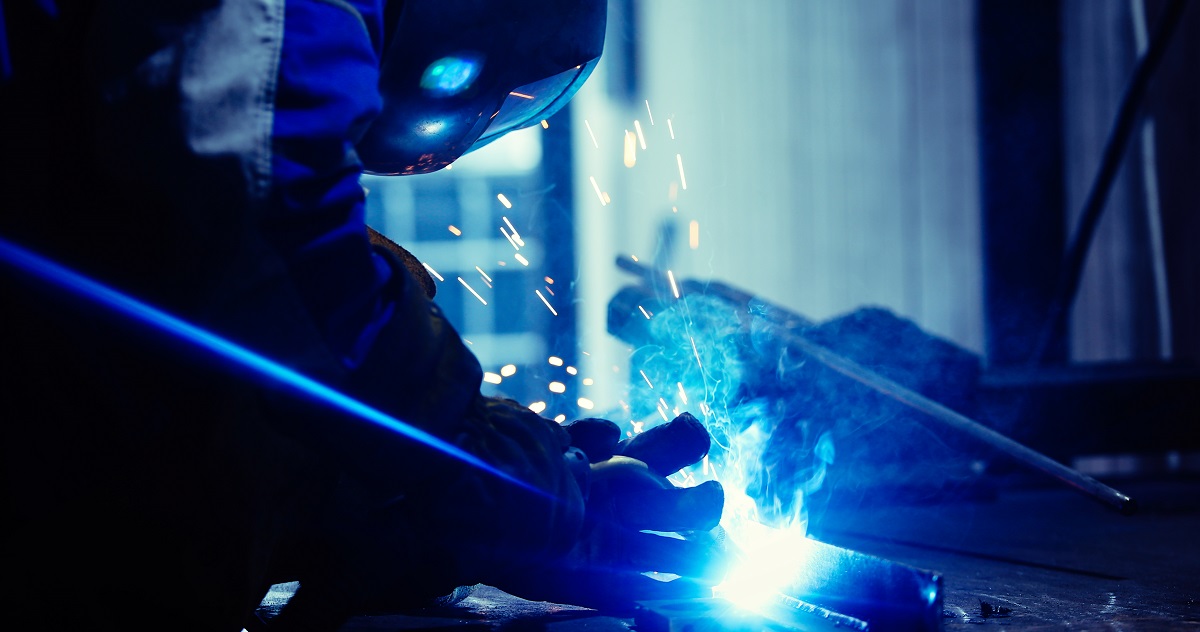 man welds at the factory working in metal industry