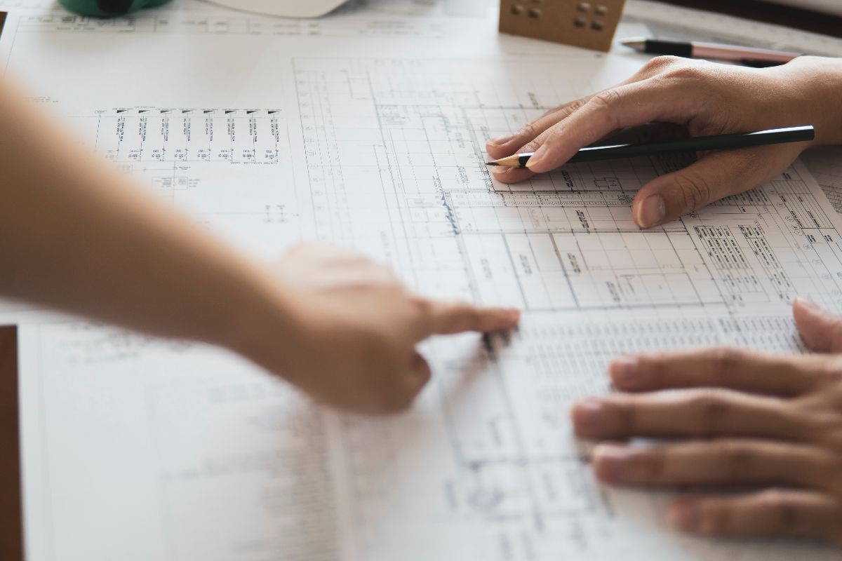 Hands reviewing construction plans and material pricing details