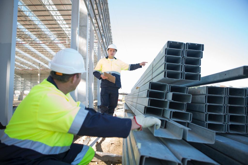 Construction workers reviewing steel materials at a building site