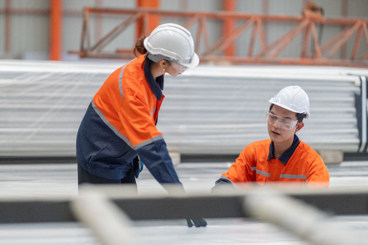 Factory workers inspecting stainless steel materials during procurement evaluation