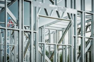 Worker standing beside a stainless steel structural frame under construction