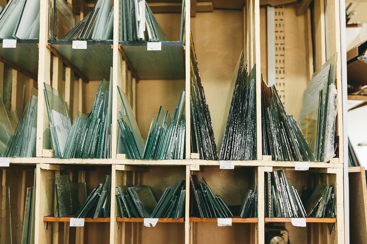 Assorted glass panels organized by size and type on wooden storage racks inside a workshop