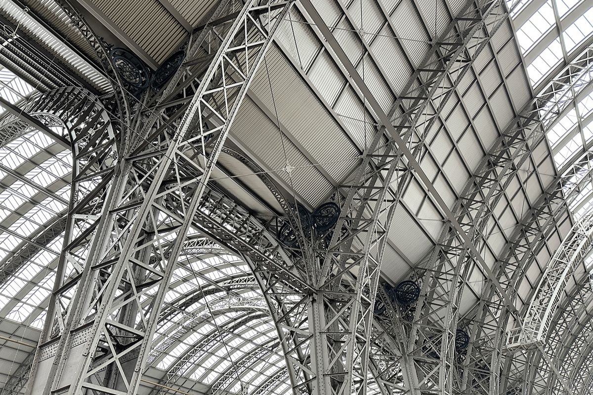 Stacks of wrapped steel beams and fabricated metal components stored inside an industrial warehouse