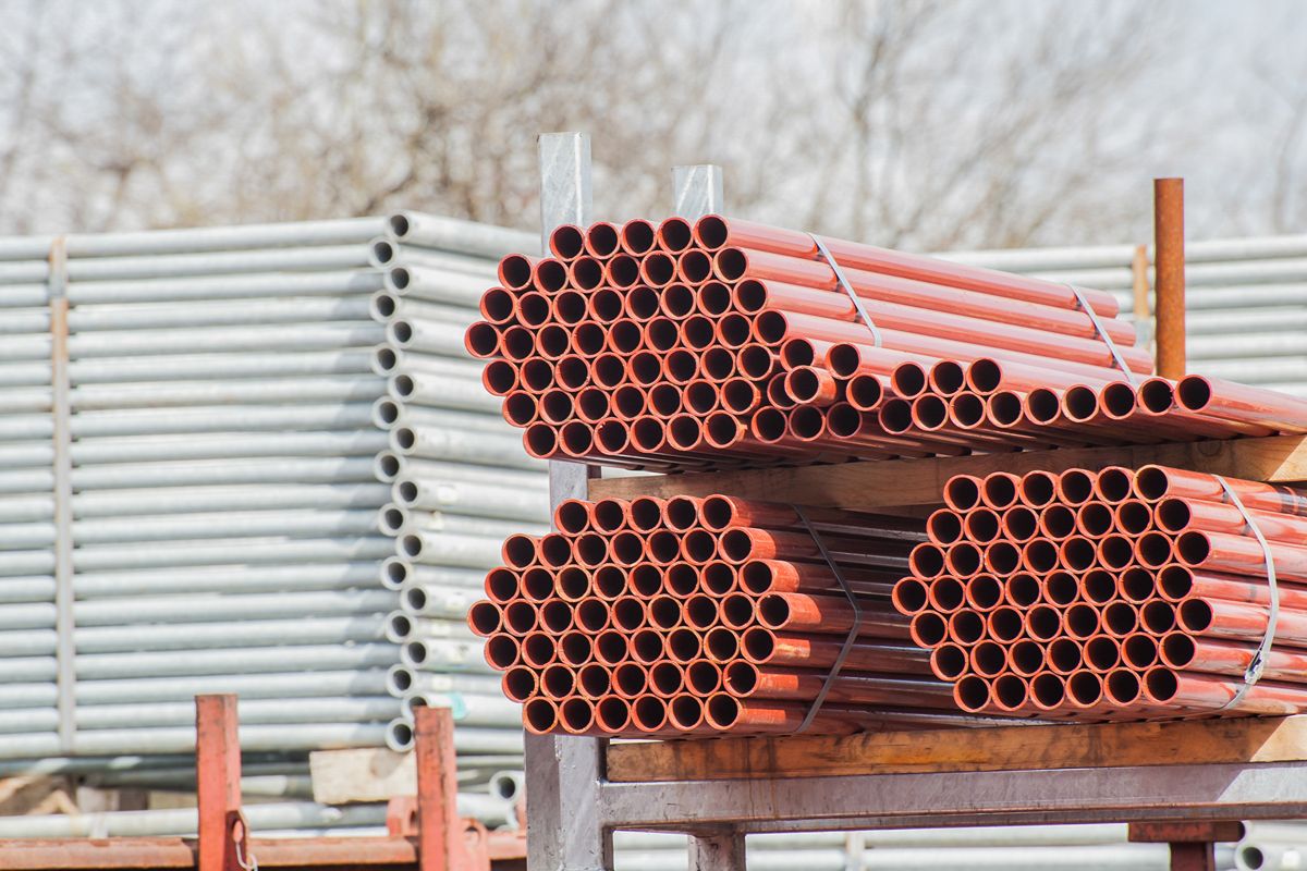 Bundles of red and galvanized steel pipes stacked outdoors for storage and distribution